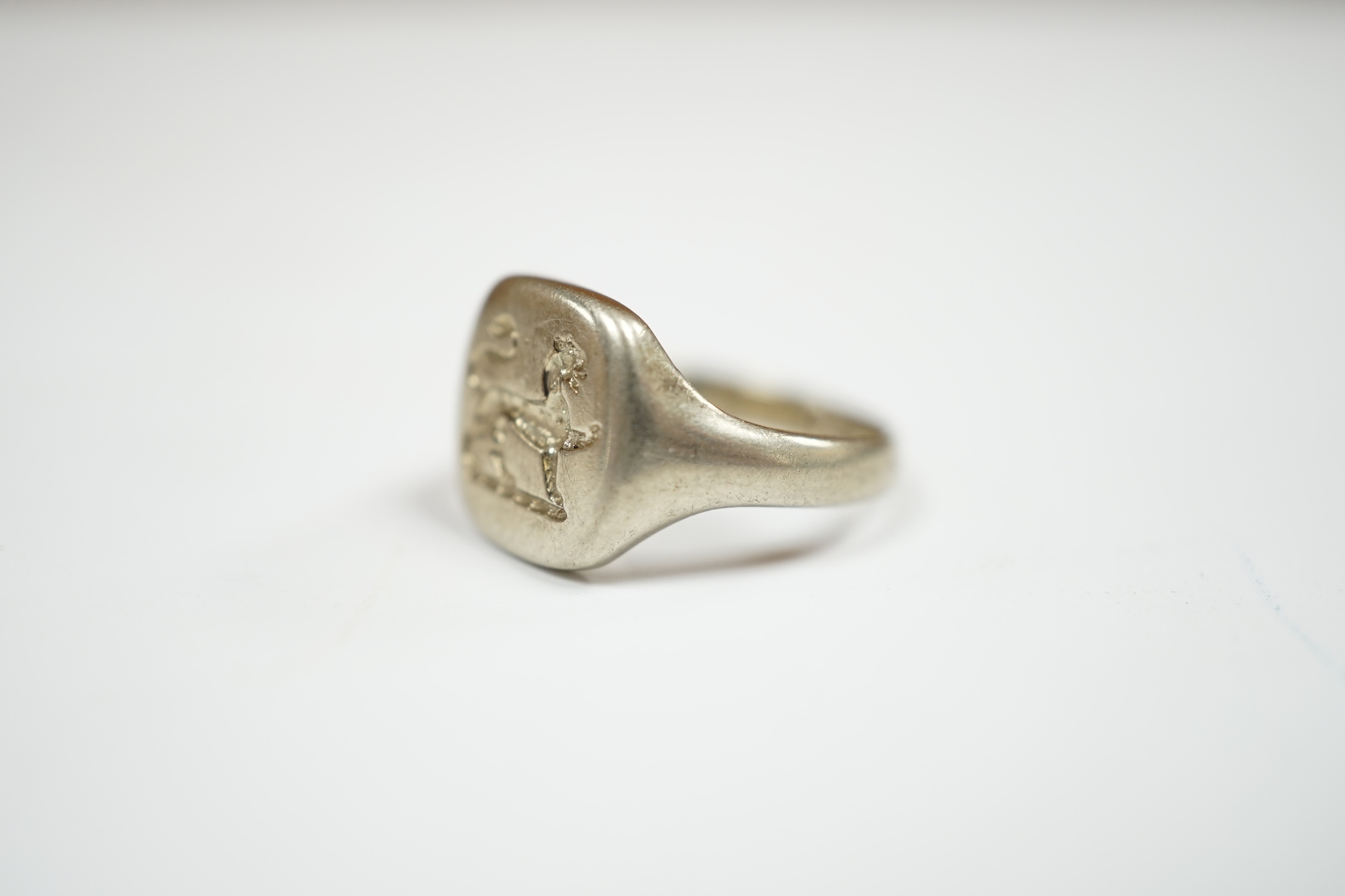A George V 18ct white gold signet ring, carved with a crest, London, 1934, size I, 5.7 grams. Condition - fair